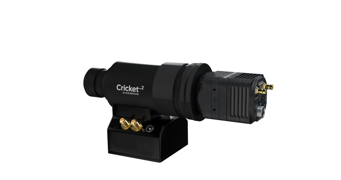 Black, cylindrical Cricket™2 imaging device mounted on a compact base, featuring a large front optical lens, textured grip rings, and front-panel controls and connectors; branded “Exosens” on the base, shown against a white background.